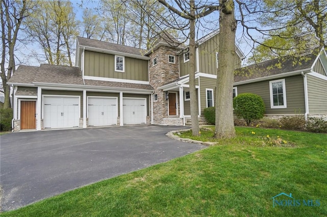 traditional-style house featuring board and batten siding, aphalt driveway, a garage, stone siding, and a front lawn