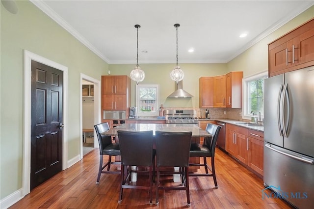 kitchen featuring a sink, a breakfast bar, stainless steel appliances, a center island, and wood finished floors