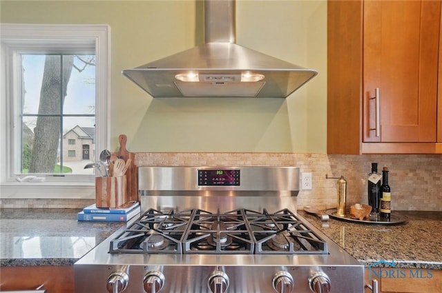 details featuring brown cabinets, island exhaust hood, stone countertops, stainless steel range with gas cooktop, and decorative backsplash