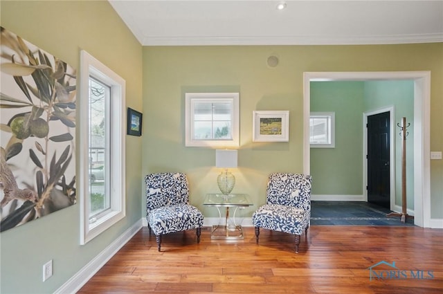 living area with a wealth of natural light, hardwood / wood-style flooring, and crown molding