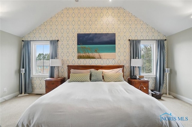 carpeted bedroom with an accent wall, multiple windows, vaulted ceiling, and baseboards