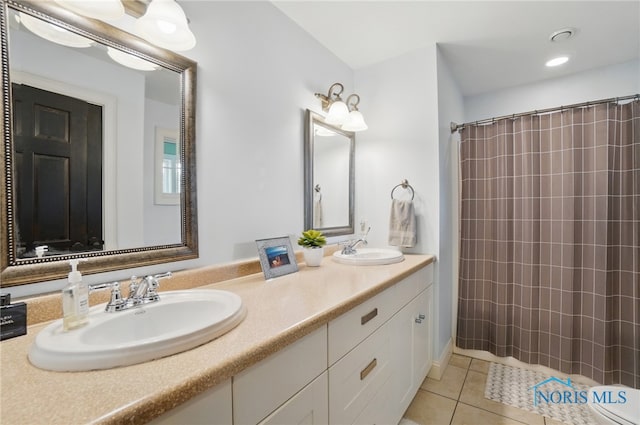 bathroom featuring tile patterned floors, a shower with shower curtain, double vanity, and a sink
