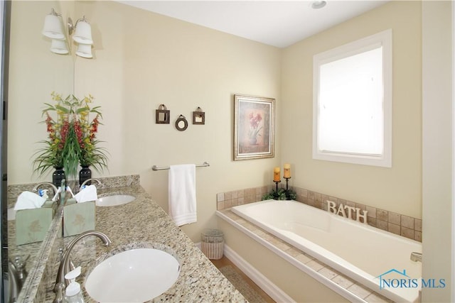 full bathroom with a garden tub, baseboards, a sink, and double vanity