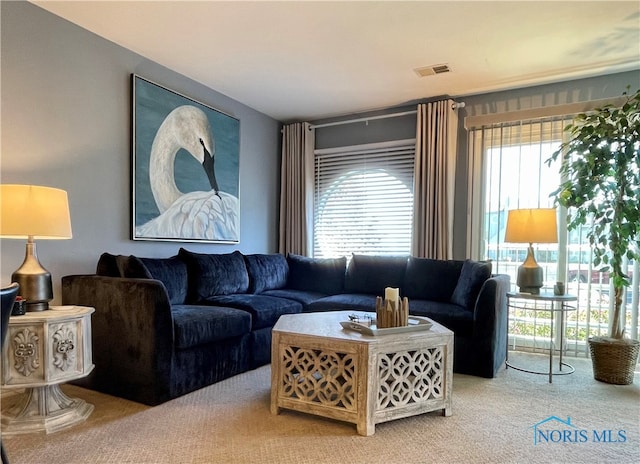 living room featuring a wealth of natural light, visible vents, and light carpet