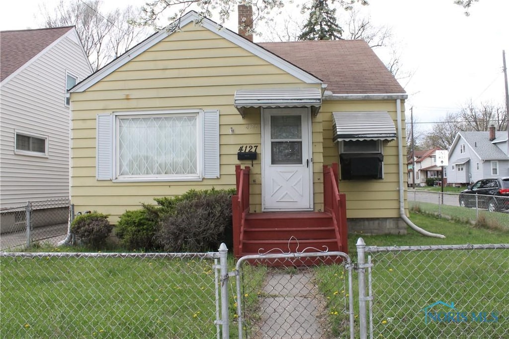 bungalow with a gate, a chimney, a front yard, and a fenced front yard