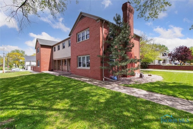 325 Park St, Bryan, OH 43506 - rear view of property featuring brick siding, a lawn, and a chimney
