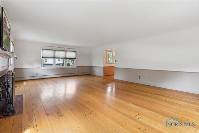 325 Park St, Bryan, OH 43506 - unfurnished living room with a fireplace, light wood-style floors, baseboard heating, a baseboard radiator, and baseboards