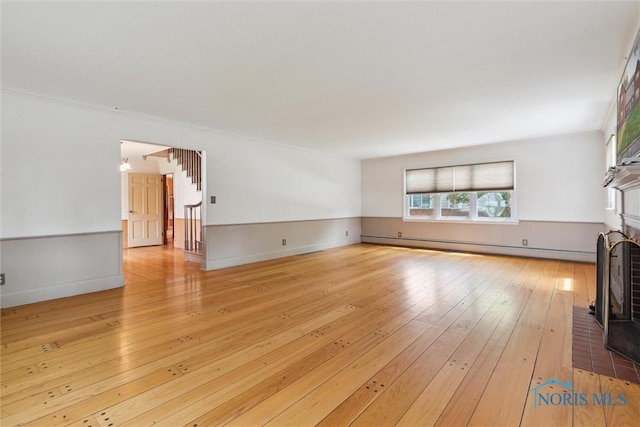325 Park St, Bryan, OH 43506 - unfurnished living room with a baseboard radiator, hardwood / wood-style floors, stairway, and a fireplace