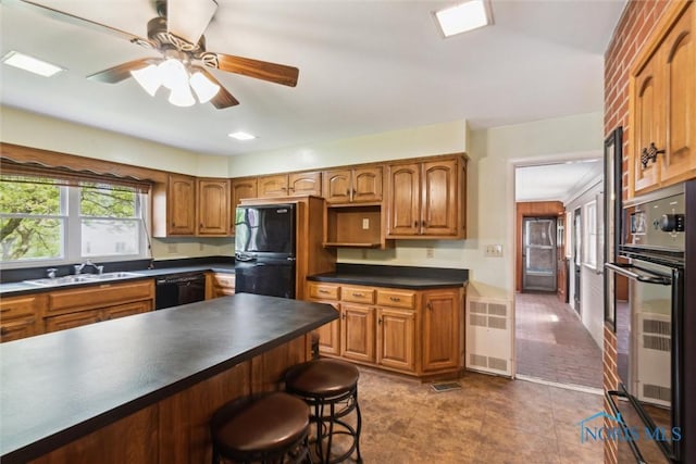 325 Park St, Bryan, OH 43506 - kitchen featuring a sink, black appliances, dark countertops, a kitchen breakfast bar, and ceiling fan