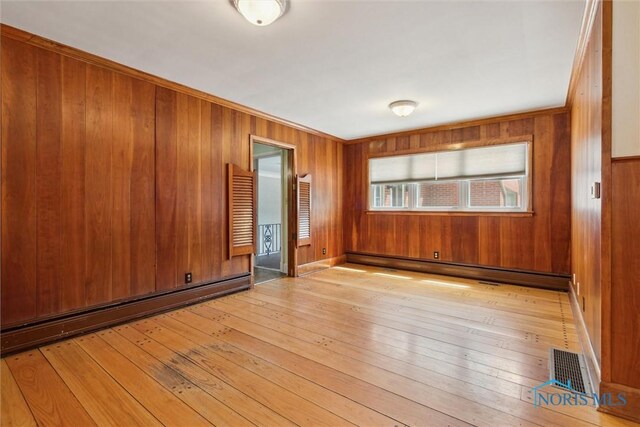 325 Park St, Bryan, OH 43506 - spare room featuring light wood-style floors, wooden walls, a baseboard heating unit, and crown molding