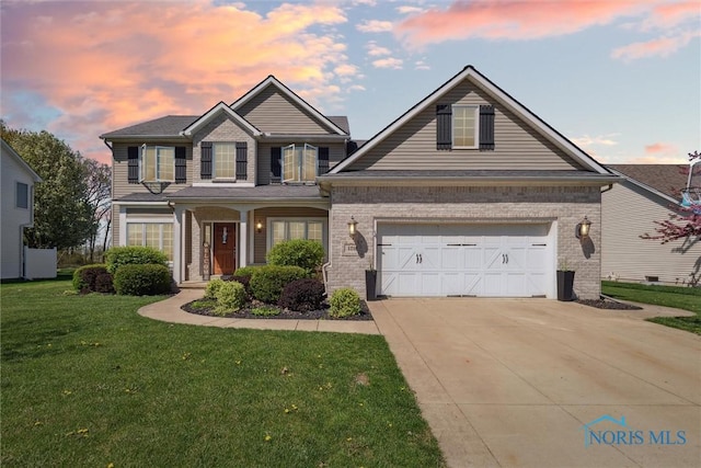 view of front of house featuring a lawn, a garage, driveway, and brick siding