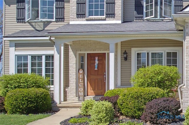 doorway to property featuring roof with shingles and a porch
