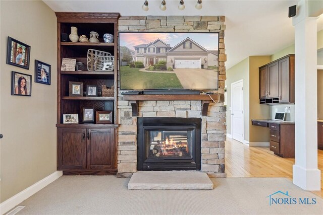 living area with carpet floors, baseboards, and a stone fireplace