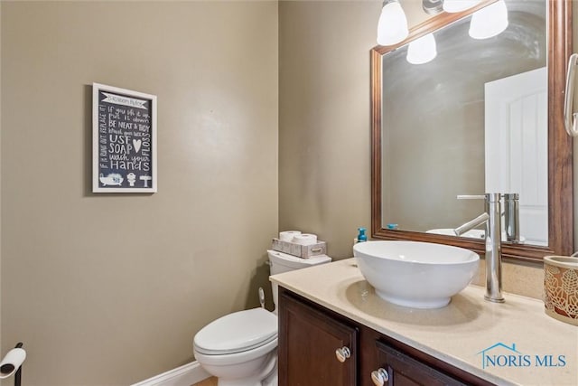 half bath featuring vanity and toilet