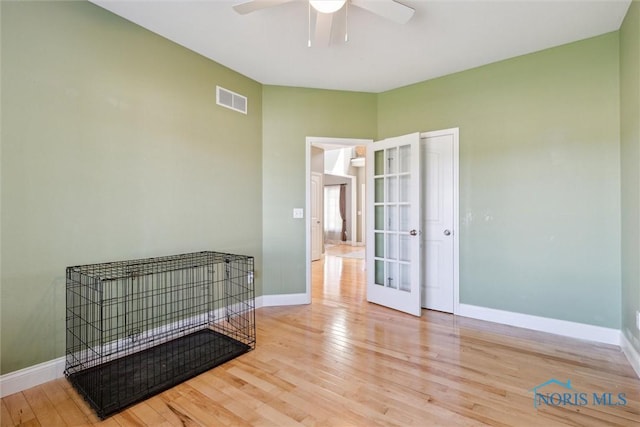 unfurnished room with visible vents, wood finished floors, baseboards, ceiling fan, and french doors