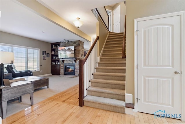 staircase featuring baseboards, wood finished floors, and a fireplace