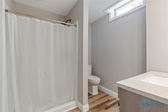 bathroom with toilet, baseboards, curtained shower, and wood finished floors