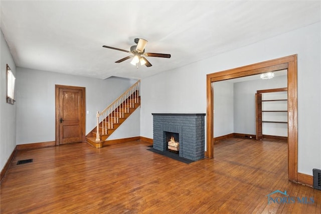2000 Oakwood Ave, Toledo, OH 43607 - unfurnished living room featuring wood finished floors, a brick fireplace, baseboards, and ceiling fan