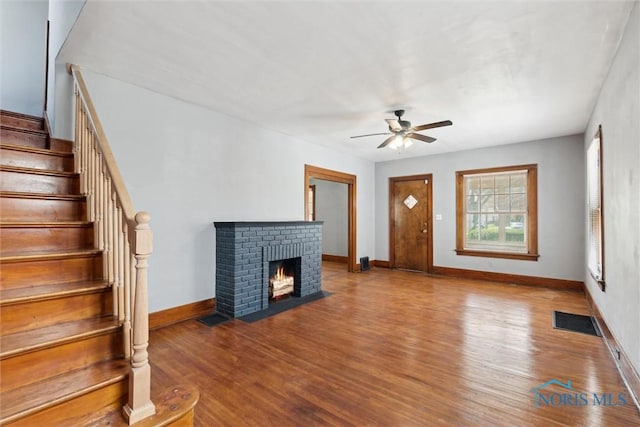 2000 Oakwood Ave, Toledo, OH 43607 - unfurnished living room featuring a ceiling fan, stairs, wood finished floors, baseboards, and visible vents
