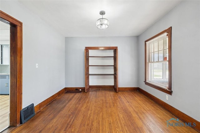 2000 Oakwood Ave, Toledo, OH 43607 - spare room with baseboards, a chandelier, wood finished floors, and visible vents