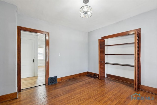 2000 Oakwood Ave, Toledo, OH 43607 - spare room with baseboards, a chandelier, wood finished floors, and visible vents