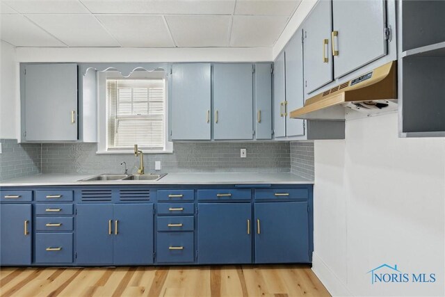 2000 Oakwood Ave, Toledo, OH 43607 - kitchen with blue cabinets, a sink, tasteful backsplash, light countertops, and under cabinet range hood