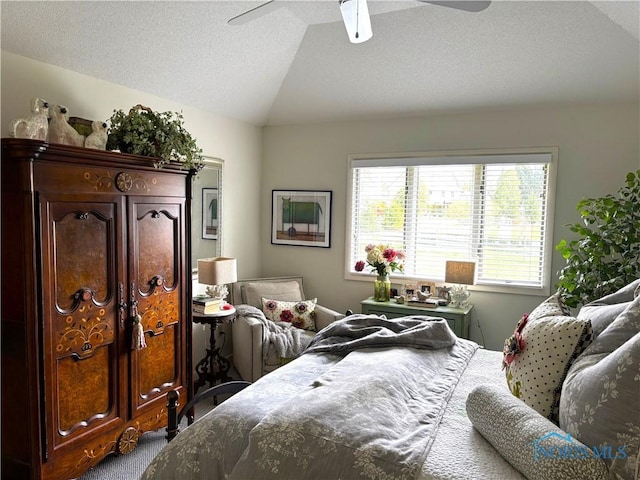 bedroom with a textured ceiling, ceiling fan, carpet flooring, and vaulted ceiling