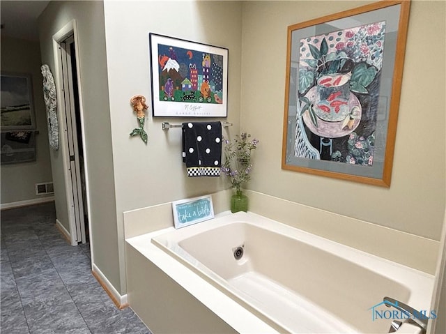 bathroom with baseboards, visible vents, and a garden tub