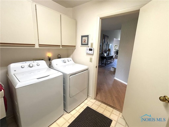 laundry room featuring baseboards, separate washer and dryer, and cabinet space