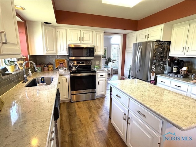 kitchen featuring appliances with stainless steel finishes, decorative backsplash, white cabinets, and a sink