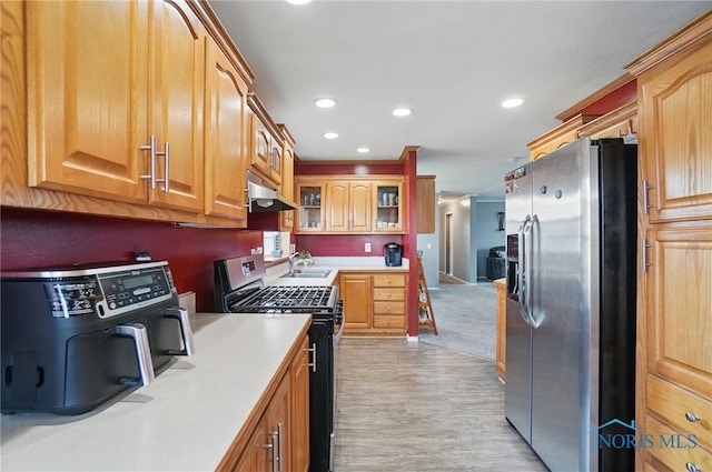 kitchen featuring a sink, recessed lighting, light countertops, under cabinet range hood, and appliances with stainless steel finishes