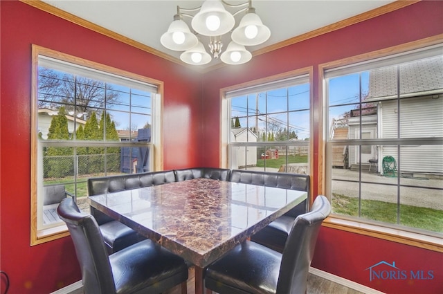 dining room with wood finished floors, baseboards, a chandelier, and crown molding