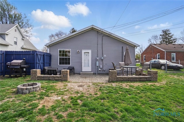 rear view of house featuring a fire pit, a patio area, a lawn, and a fenced backyard