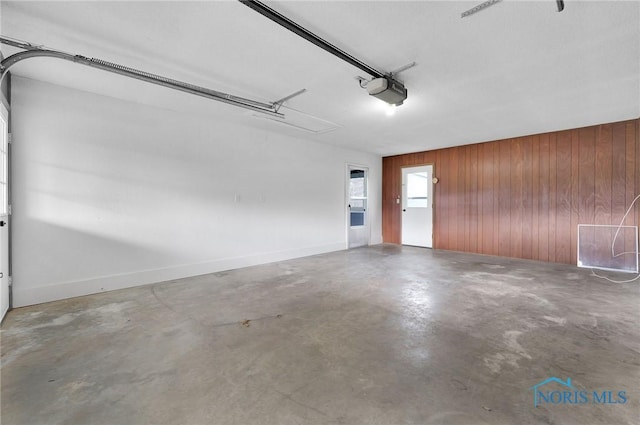 garage with wooden walls, baseboards, and a garage door opener