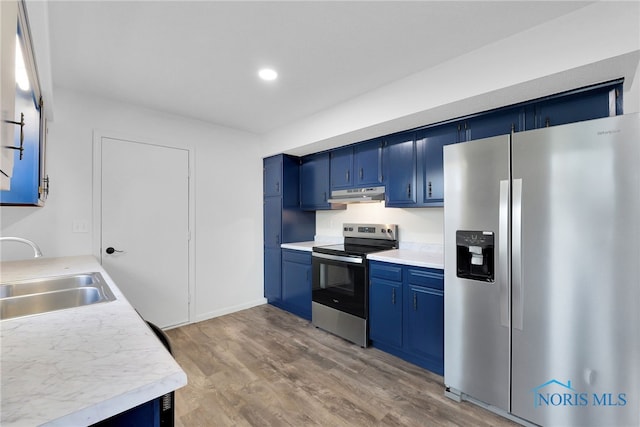 kitchen featuring stainless steel appliances, a sink, blue cabinetry, light countertops, and under cabinet range hood