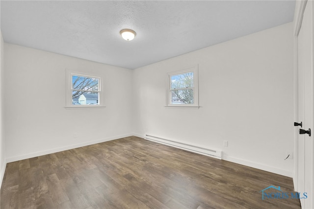 spare room featuring baseboards, baseboard heating, and wood finished floors