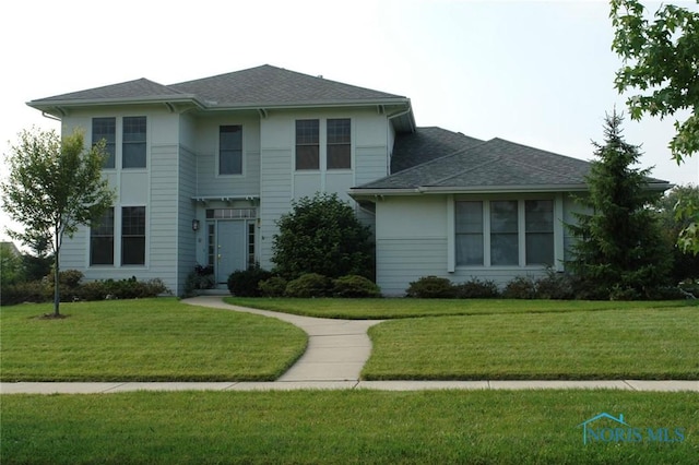 view of front of property with roof with shingles and a front lawn