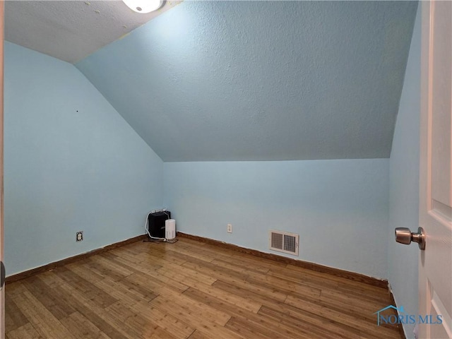 713 E Crocker St, Bradner, OH 43406 - additional living space featuring lofted ceiling, wood finished floors, visible vents, baseboards, and a textured ceiling