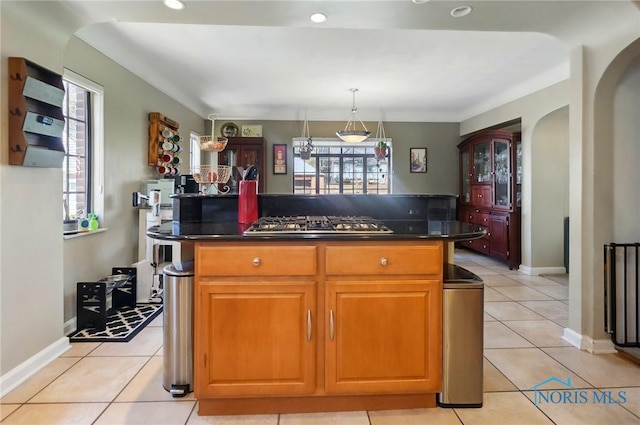 3122 Hopewell Pl, Toledo, OH 43606 - kitchen with stainless steel gas cooktop, light tile patterned floors, a center island, dark countertops, and arched walkways