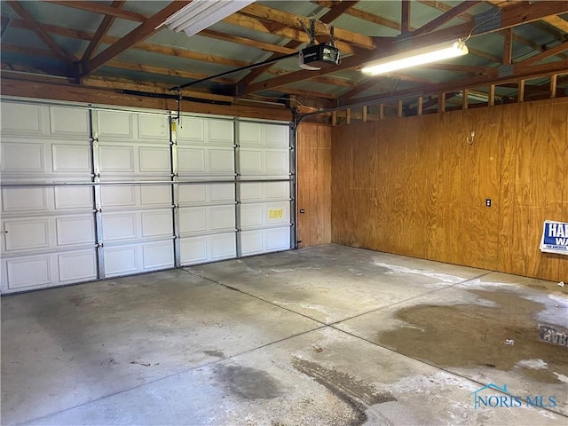 garage with a garage door opener and wood walls