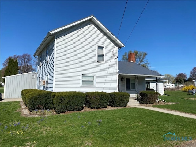 view of side of home featuring a lawn and covered porch