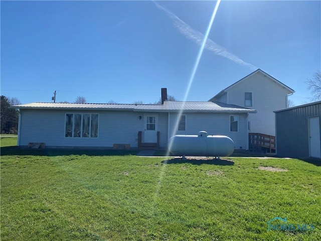 rear view of property with a yard and metal roof