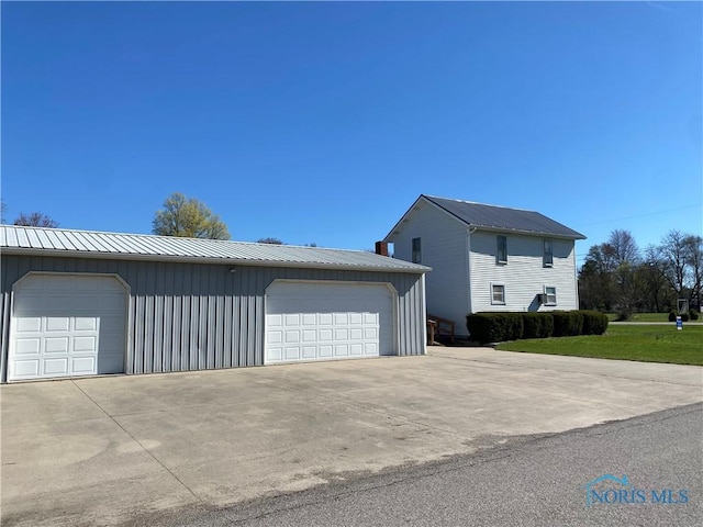 view of side of home featuring board and batten siding, an outbuilding, metal roof, and a garage