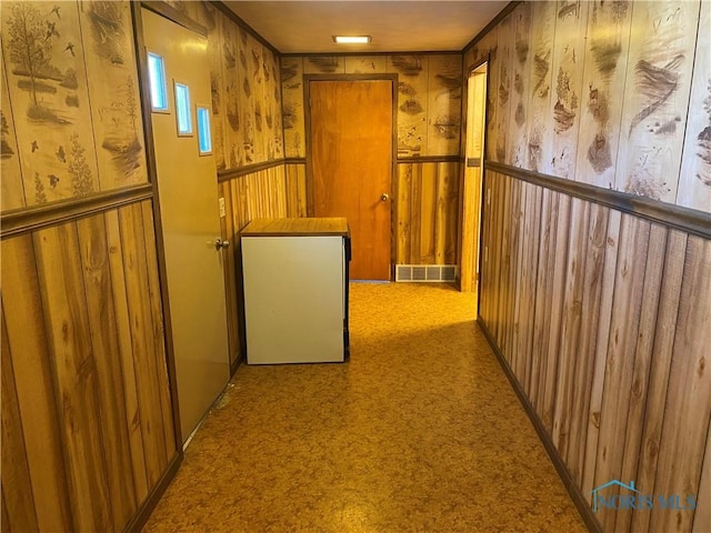hallway featuring wainscoting, visible vents, and carpet