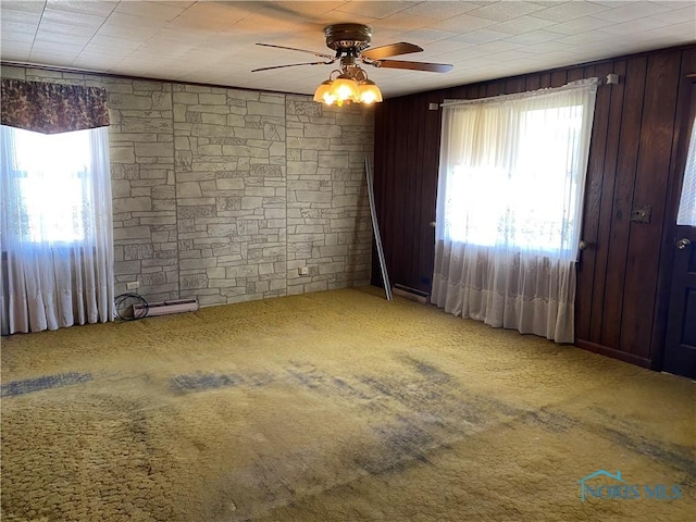 unfurnished room featuring carpet floors, a ceiling fan, and wooden walls