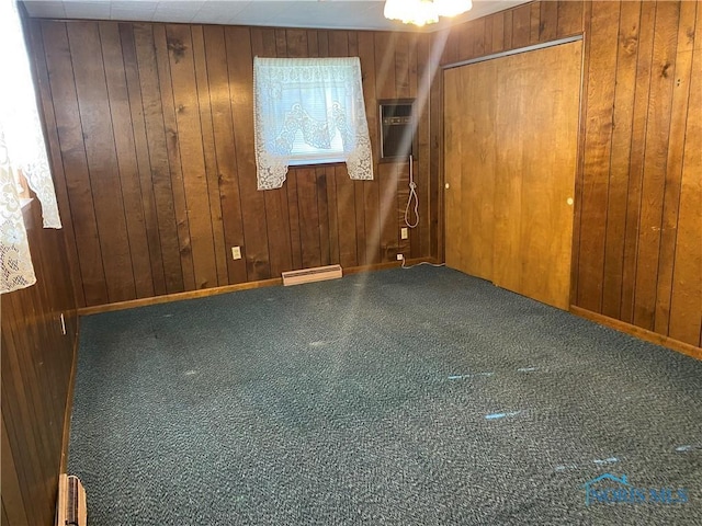 carpeted empty room featuring a baseboard heating unit, wood walls, and a wall unit AC