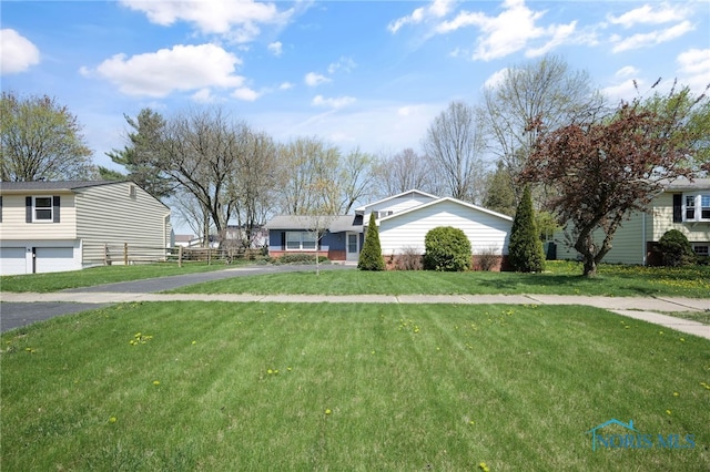 view of front of property with a front yard, fence, an attached garage, and aphalt driveway