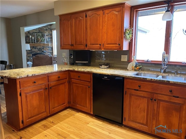 kitchen with dishwasher, brown cabinetry, a sink, and light wood finished floors
