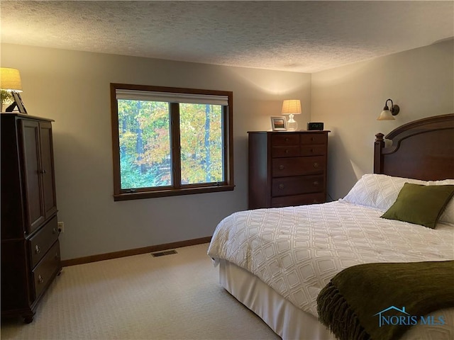 bedroom with light colored carpet, baseboards, a textured ceiling, and visible vents