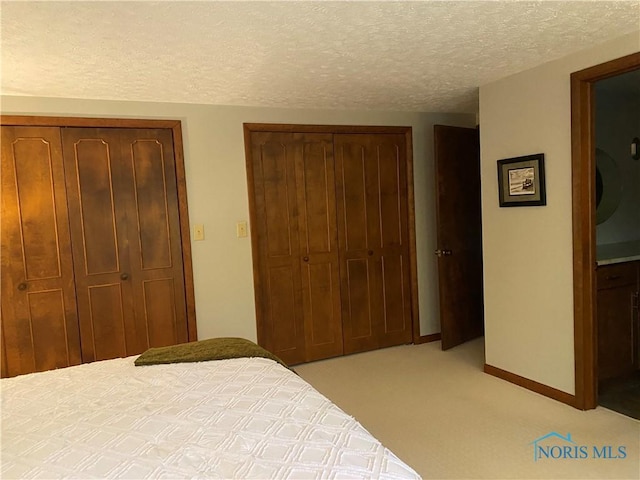 bedroom with light colored carpet, baseboards, a textured ceiling, and a closet